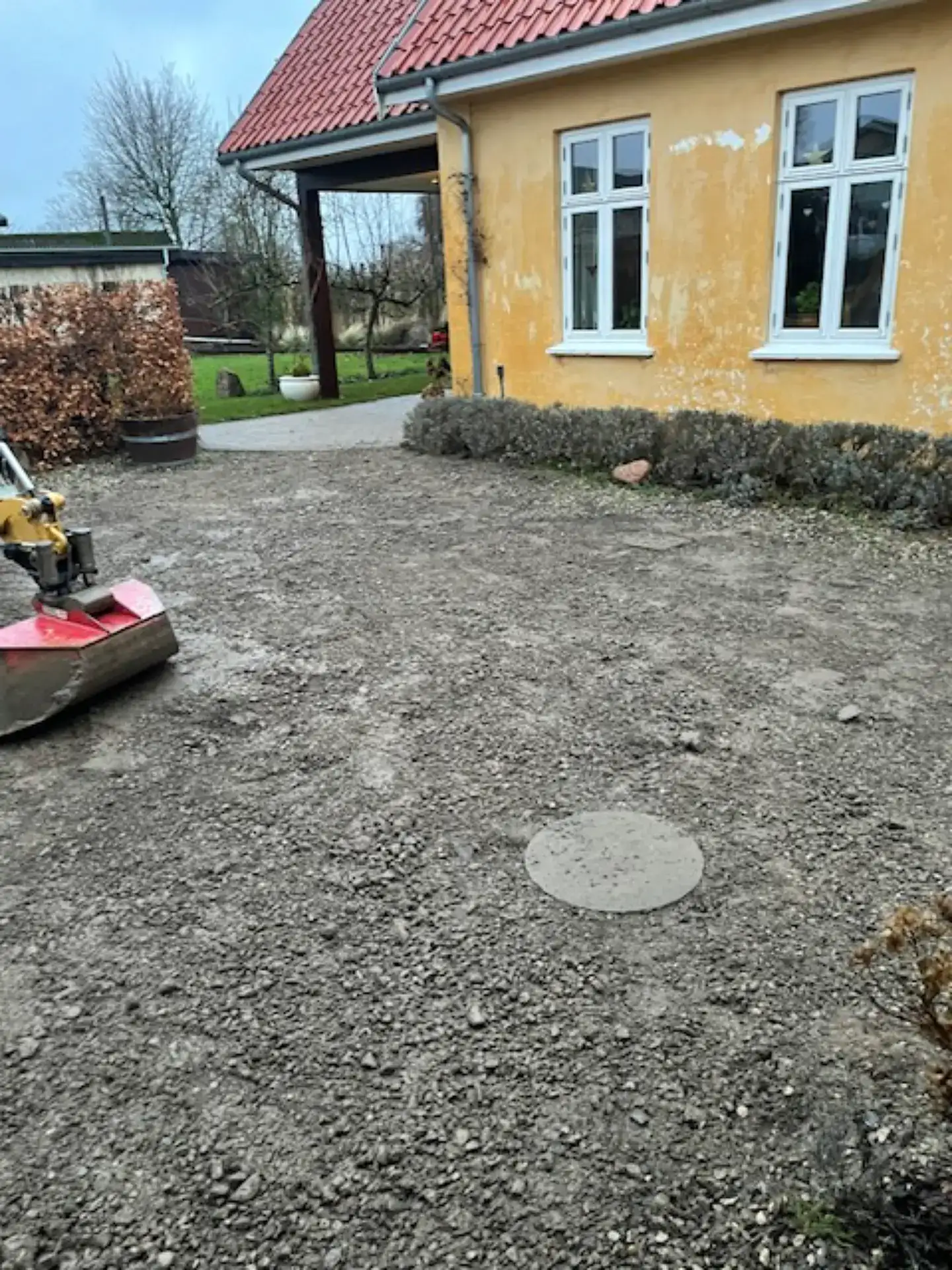 Forberedelse af haveareal med jord- og grusarbejde foran huset.