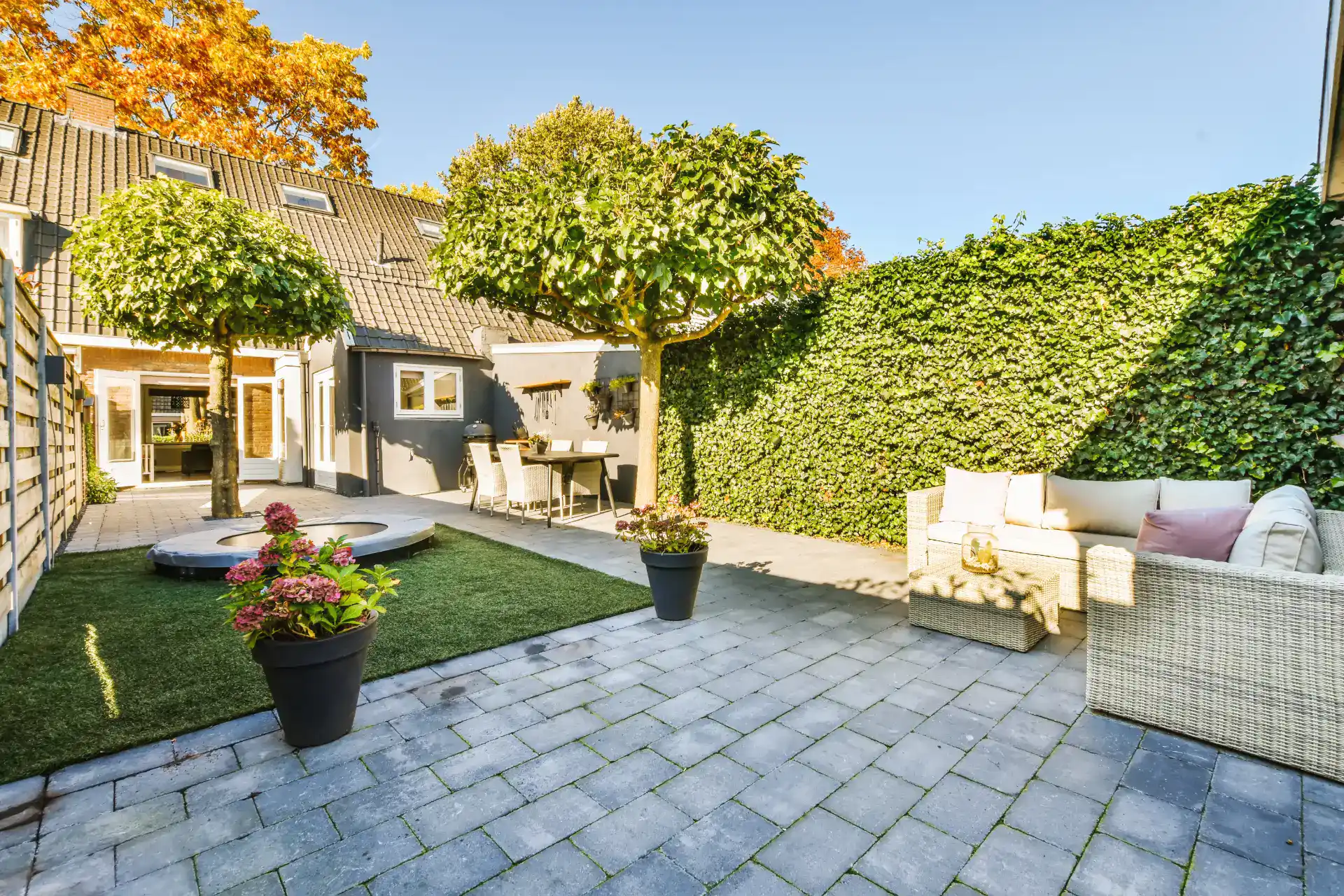 Havedesign med terrasse, siddeområde og grønne planter i baghaven. Perfekt til afslapning og udendør.