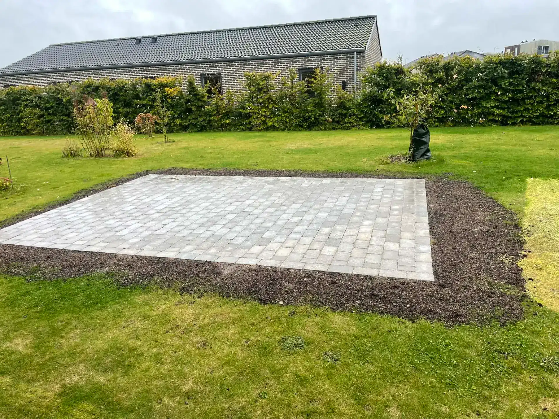 Nybelagt terrasse med belægningssten i haven.